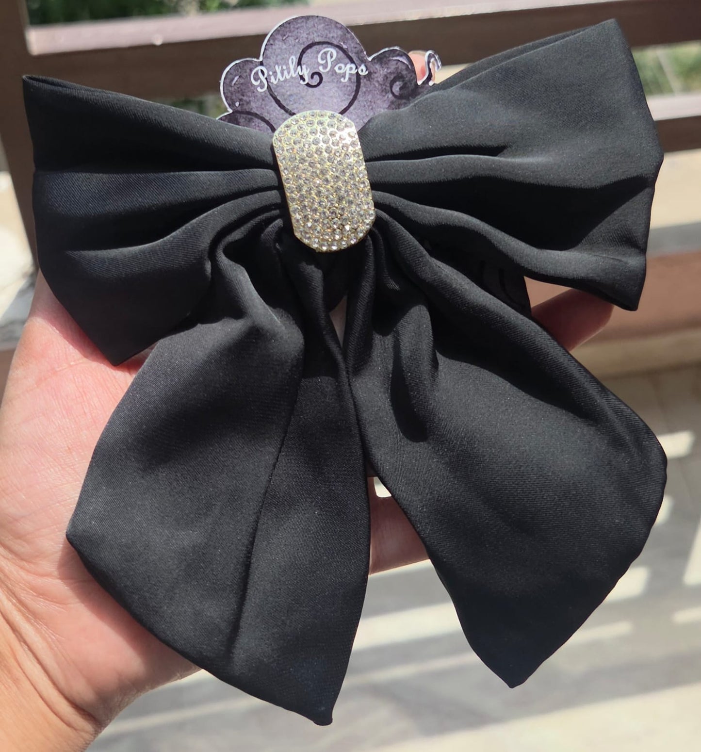 Luxury midnight black satin hair bow clip with a glittering crystal centerpiece for formal hairstyles