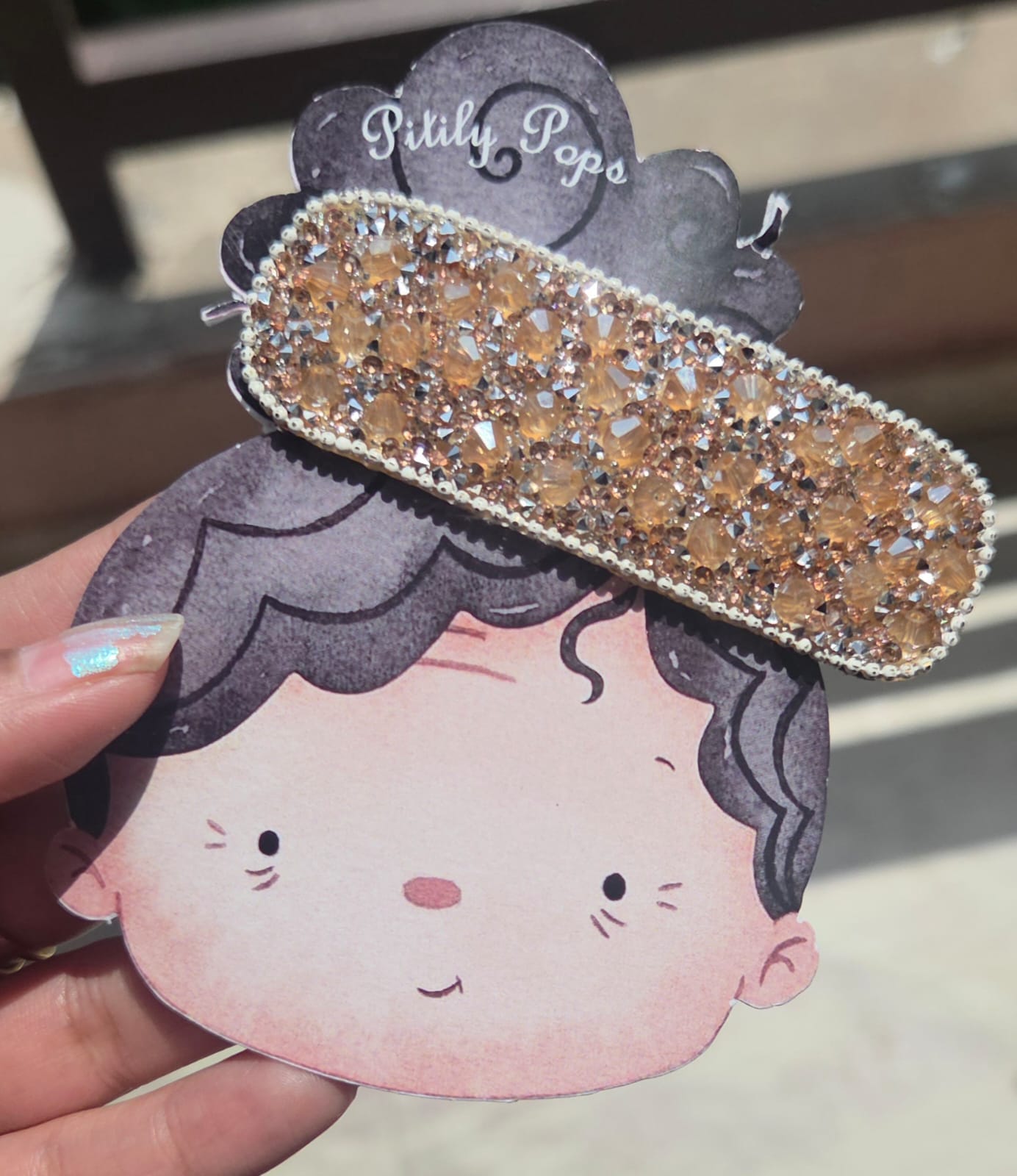 Shimmering rose gold crystal encrusted rectangular hair clip on a Pitily Pops cartoon backing card.