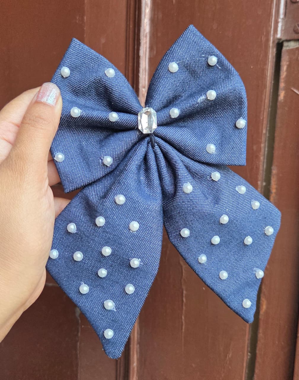 Handmade blue denim tail hair bow clip embellished with scattered faux pearls and a large central crystal rhinestone gem.