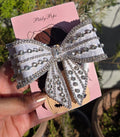 Handmade white satin crystal hair bow clip by Pitily Pops featuring rows of glittering rhinestones