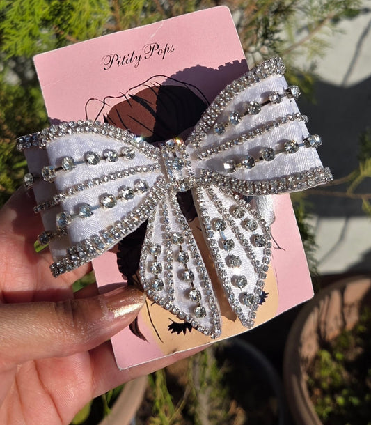 Handmade white satin crystal hair bow clip by Pitily Pops featuring rows of glittering rhinestones