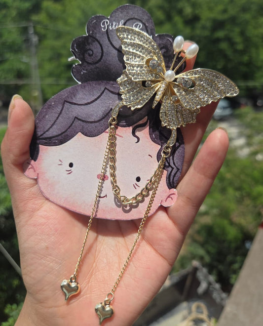 Aesthetic gold butterfly hair clip with alligator backing and dangling heart charms, ideal for wedding guest or party hairstyles