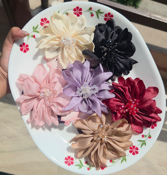 Pitily Pops floral clip collection showcasing handcrafted fabric flower hair clips with pearls in 6 colors: white, black, pink, purple, red, and gold.