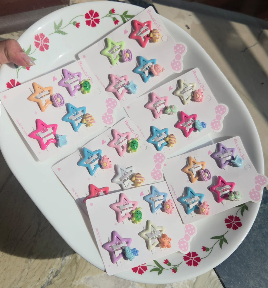 Cute pastel colored star hair accessories for kids showing four colorful metal snap clips in purple, orange, blue, and pink decorated with ocean theme resin characters.