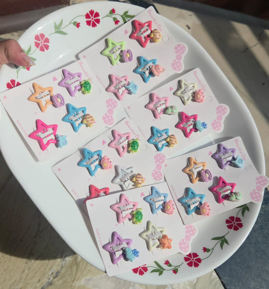 Cute pastel colored star hair accessories for kids showing four colorful metal snap clips in purple, orange, blue, and pink decorated with ocean theme resin characters.