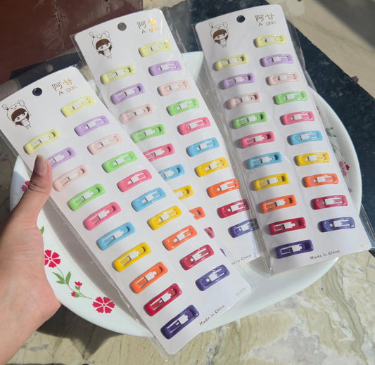 Handheld shot of Pitily Pops multi-color pastel matte snap clips card featuring rainbow colors like pink, purple, yellow, and blue.