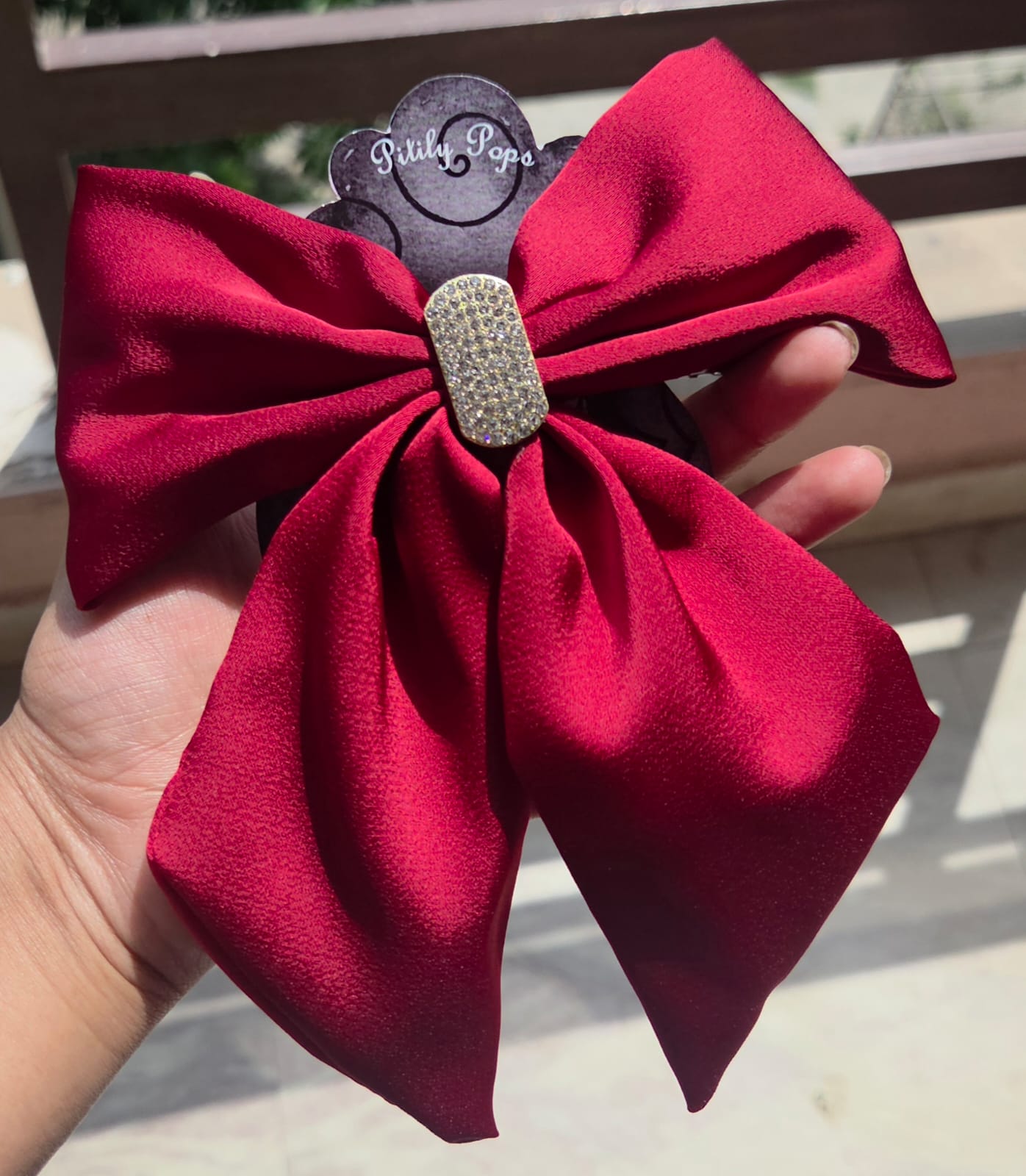 Premium crimson red satin oversized hair bow featuring a rhinestone embellished center buckle