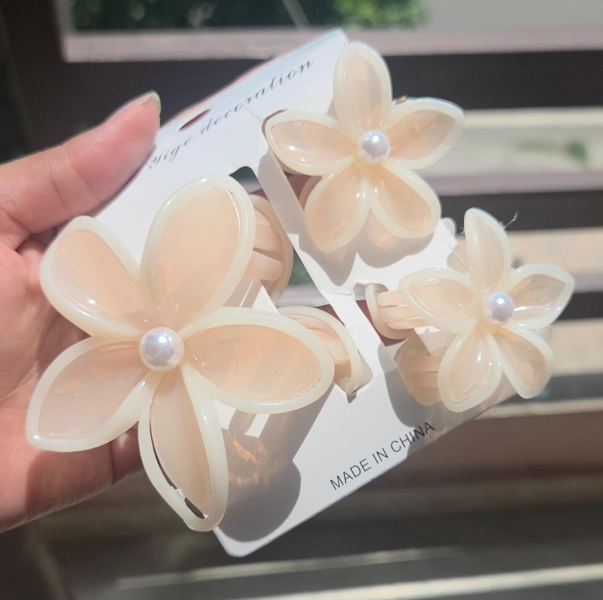 A 3-piece aesthetic floral hair jaw clip set featuring 1 big and 2 small plumeria clutchers in a warm pastel peach sorbet color.