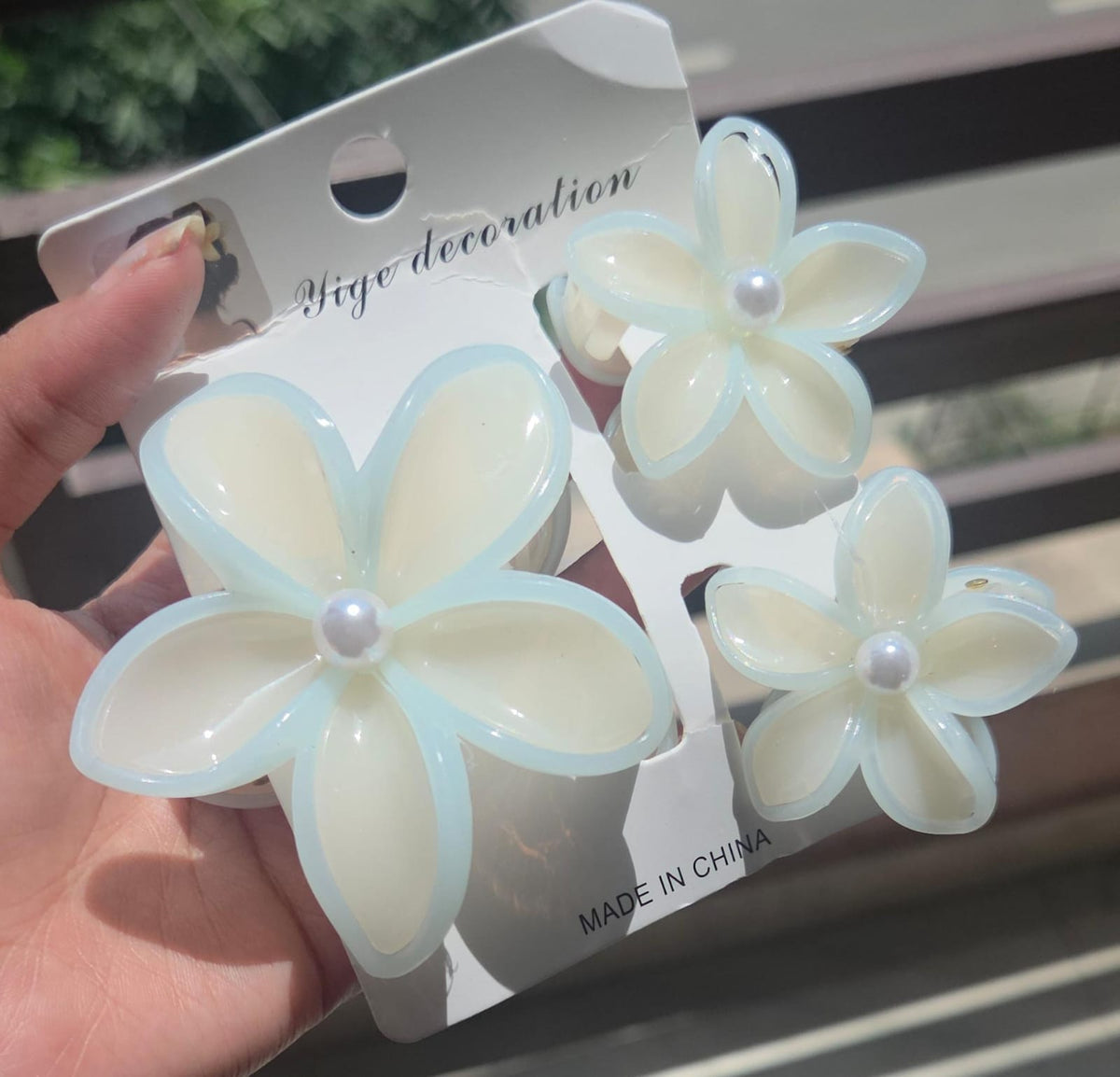 A 3-piece flower hair clutcher set featuring 1 large and 2 small plumeria claw clips in vanilla cream with a soft mint blue border and pearl centers.