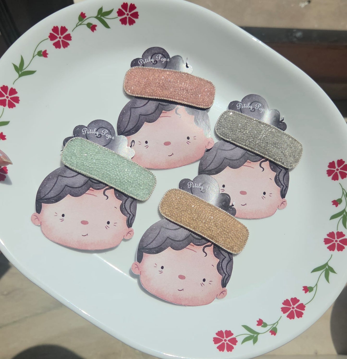our luxury rhinestone crystal snap hair clips in sparkling mint green, blush pink, diamond silver, and champagne gold displayed together on a white floral plate.
