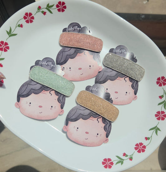 our luxury rhinestone crystal snap hair clips in sparkling mint green, blush pink, diamond silver, and champagne gold displayed together on a white floral plate.