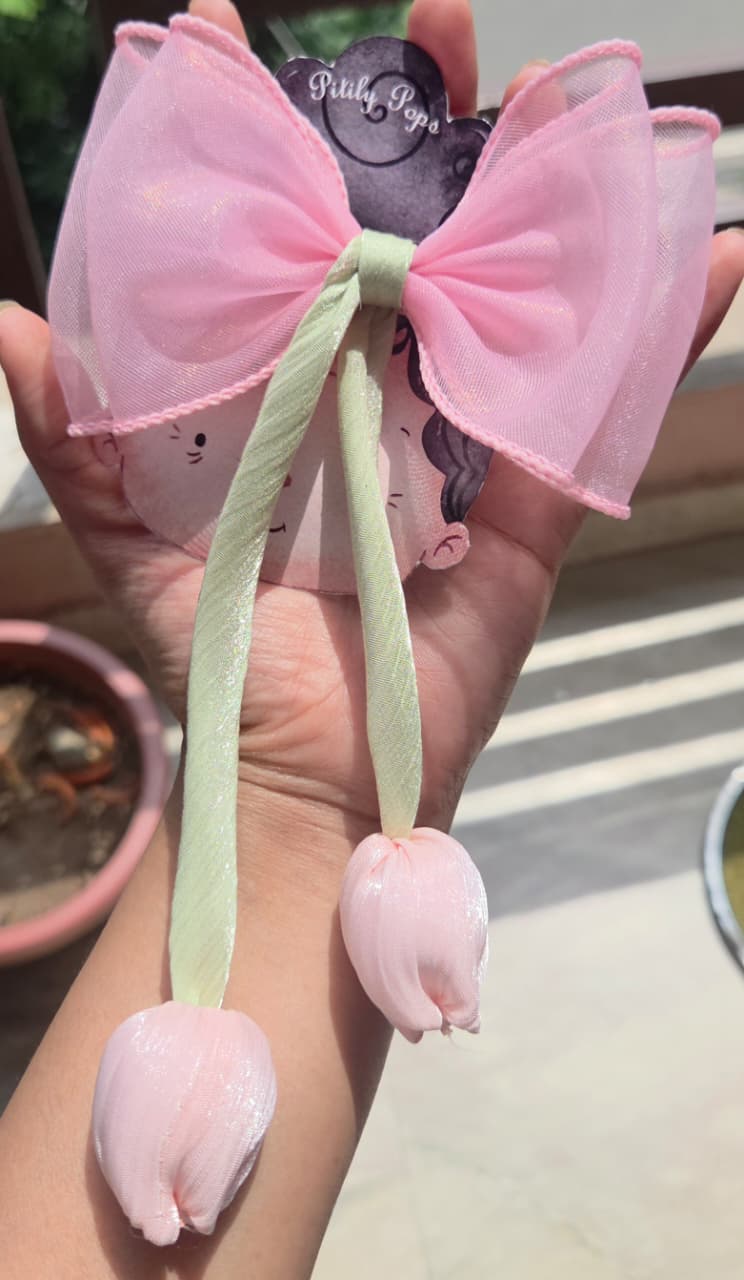 Soft petal pink translucent fabric hair bow clip featuring a trailing handmade pink tulip dangle accessory.
