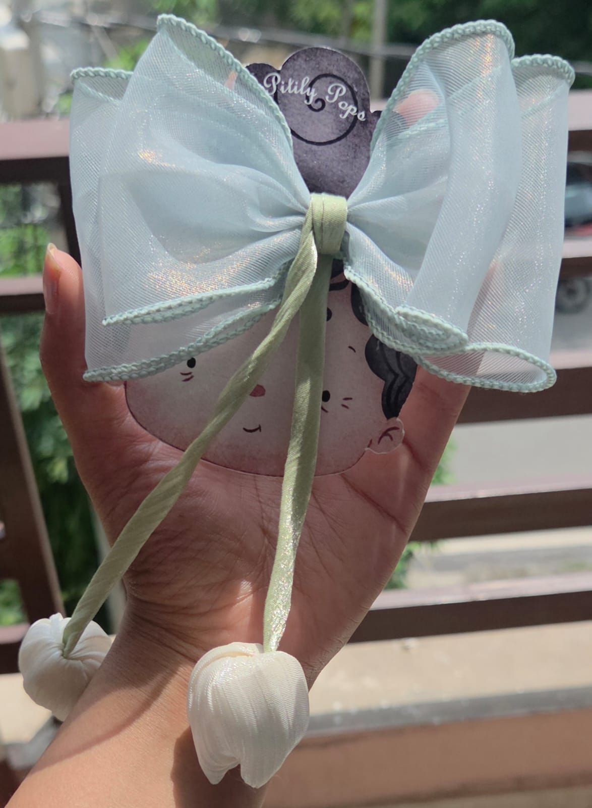 Pastel mint green organza fabric hair bow with a dangling green tulip flower accent piece, handmade by Pitily Pops.
