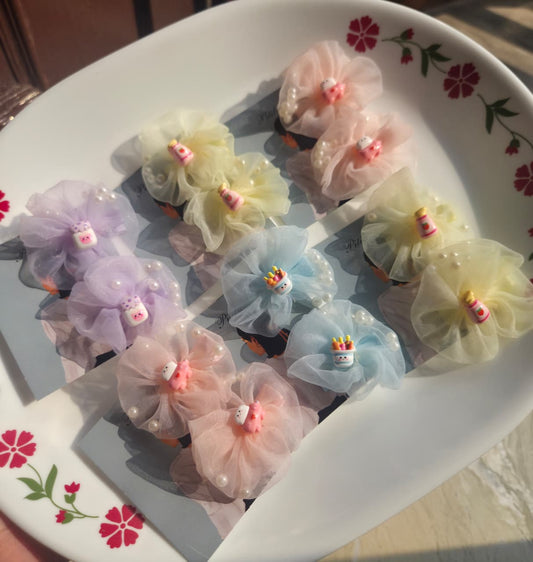 Four pairs of pastel tulle flower kids hair clips in lavender, pink, yellow, and blue with pearl accents and cute charms.