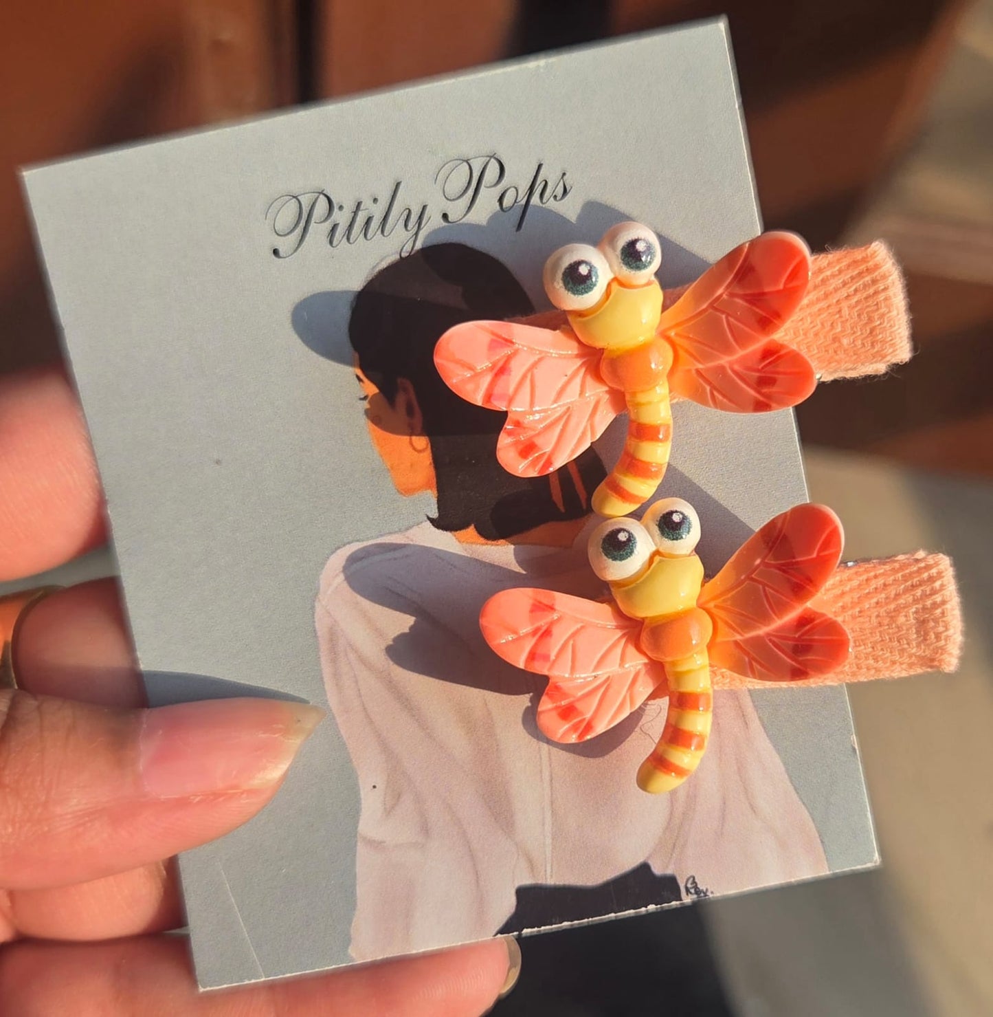 Pair of cute yellow bear-faced bee hair clips for kids on yellow fabric