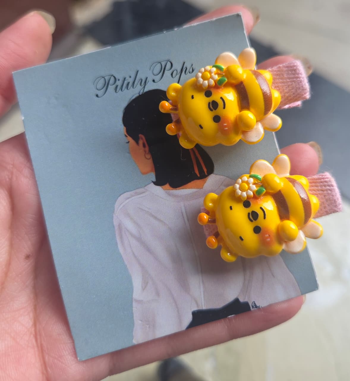 Pair of adorable flower-crowned bumblebee hair clips for girls on pink fabric-wrapped alligator clips