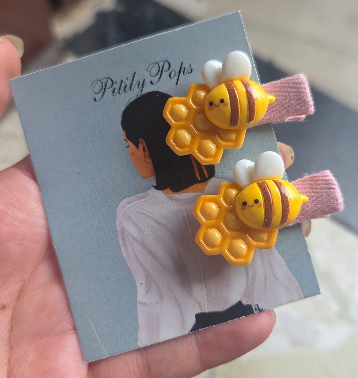 Pair of unique yellow and brown striped honeybee hair clips for toddlers on soft yellow fabric pins