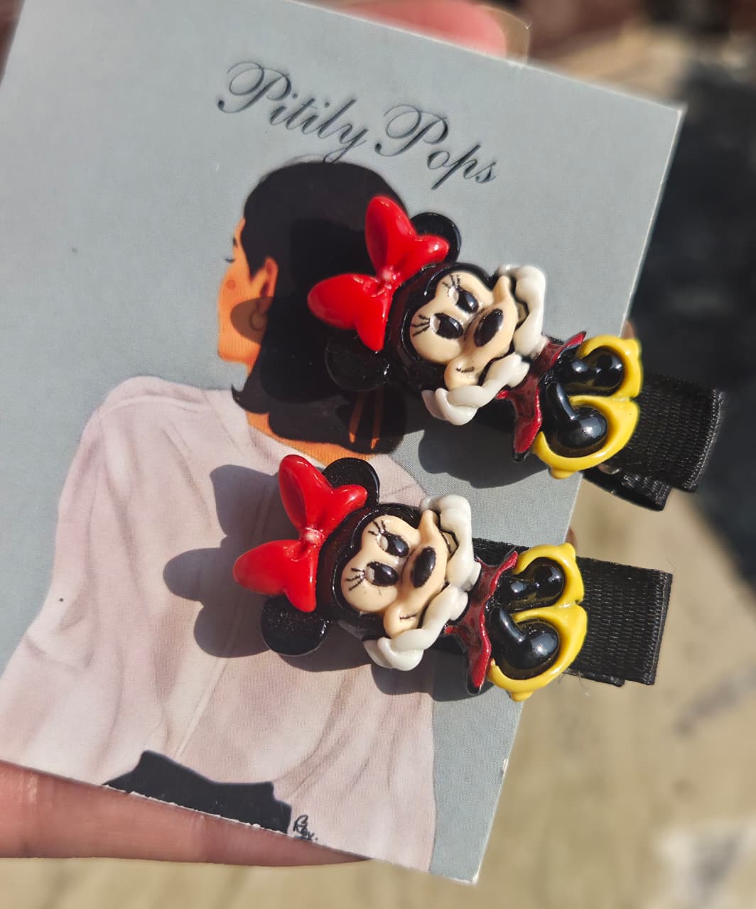 Pair of cute Minnie Mouse character hair clips with red bows on black ribbon-lined alligator pins for toddlers.