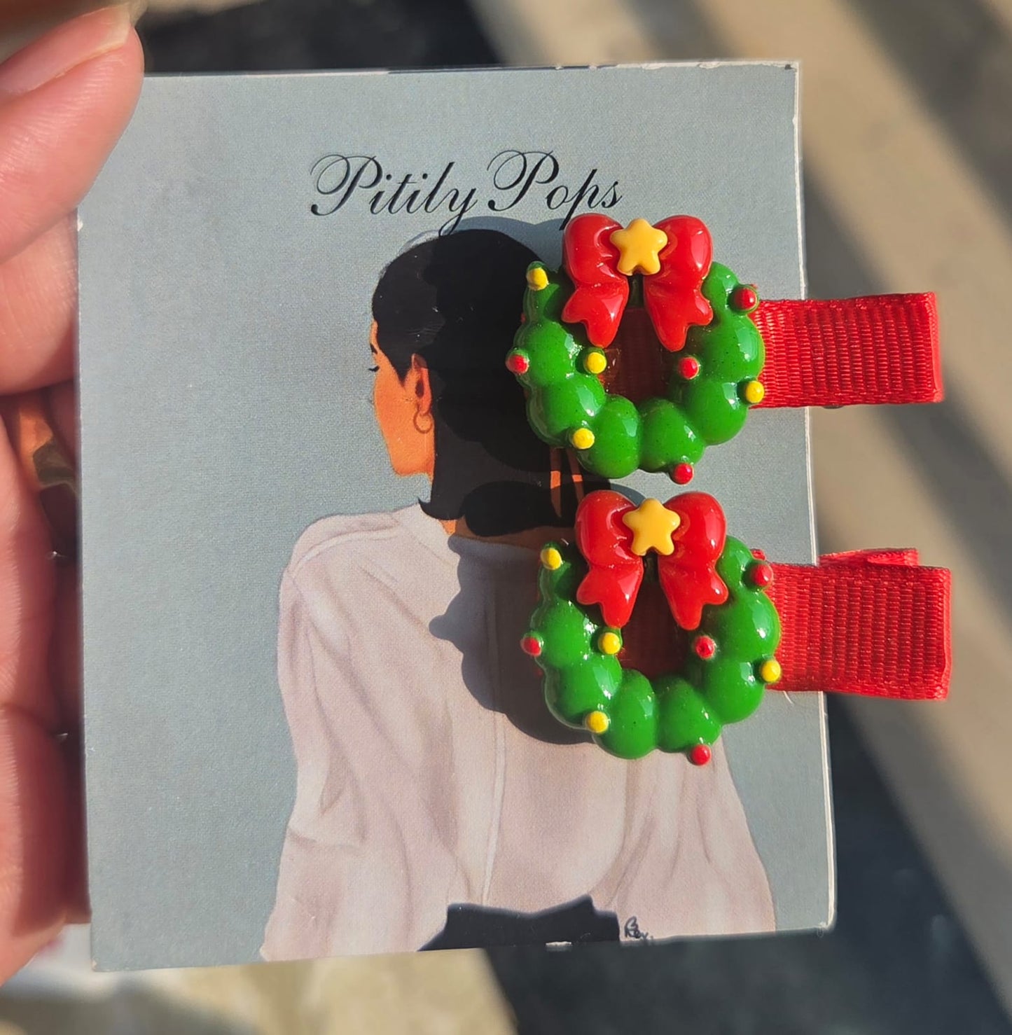 Ribbon-lined alligator hair clips for toddlers featuring 3D holiday resin charms including Christmas trees, wreaths, and Santa hats.