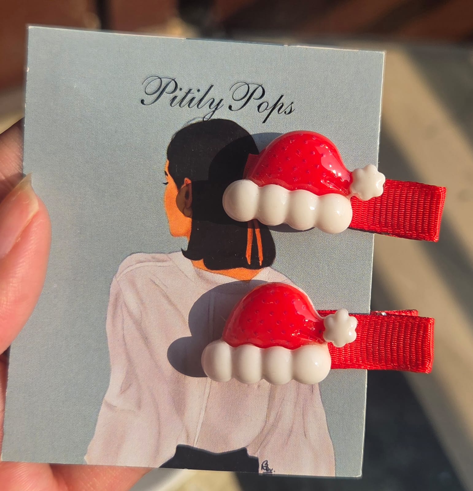 A collection of 6 pairs of colorful Christmas hair clips for kids, displayed on a white plate in natural light.