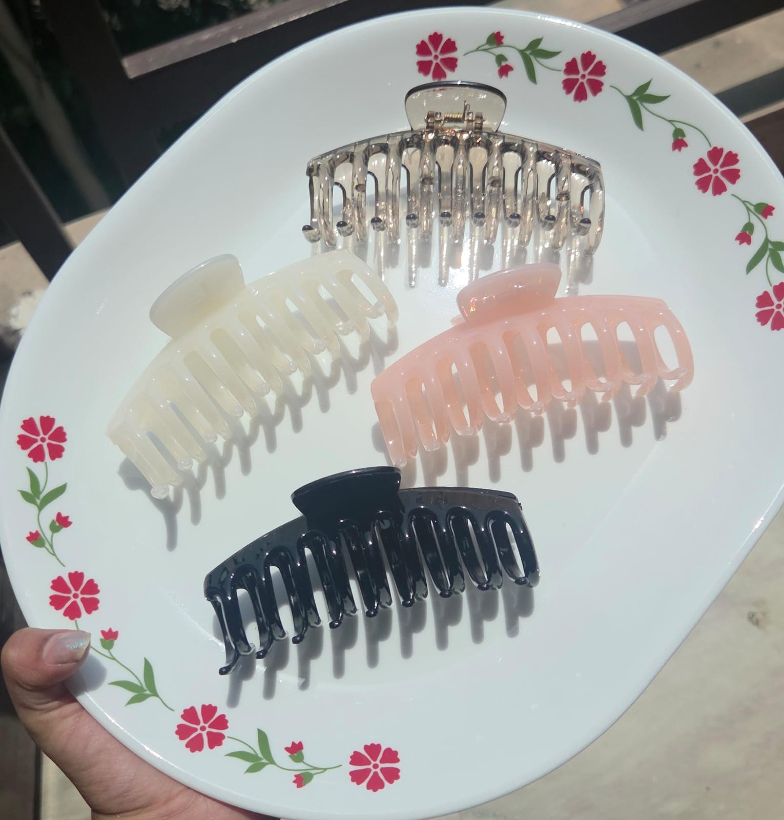 Individual aesthetic claw clips in amber, cream, pastel pink, and black colors on a white plate.