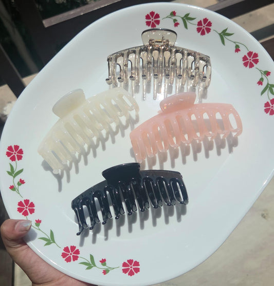 Individual aesthetic claw clips in amber, cream, pastel pink, and black colors on a white plate.