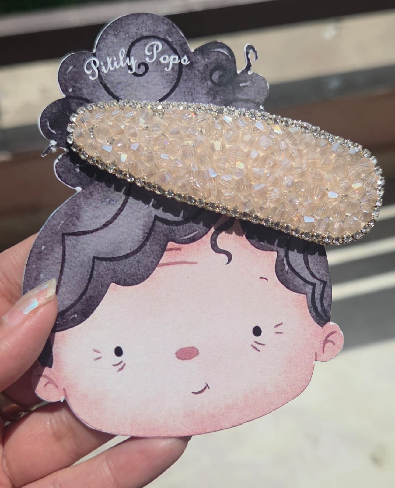 Handcrafted iridescent white crystal hair clip with a rhinestone border by Pitily Pops.
