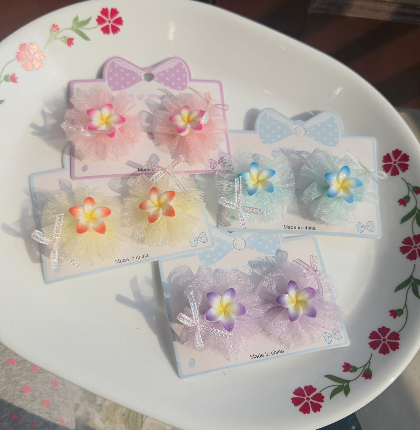 Pair of kids pastel tulle flower hair clips in pink, blue, purple, and yellow on display