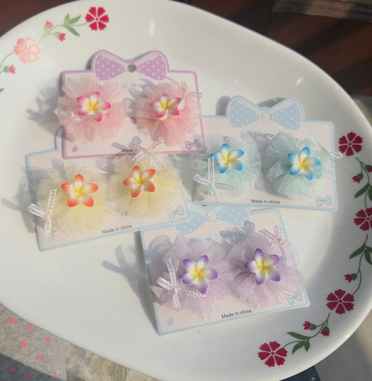 Pair of kids pastel tulle flower hair clips in pink, blue, purple, and yellow on display