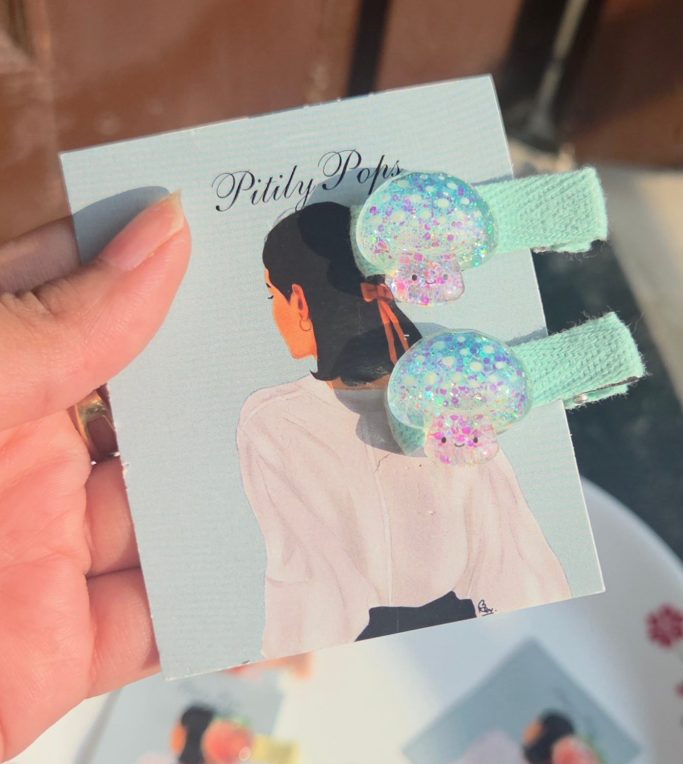 A pair of pastel mint green handmade alligator clips topped with iridescent glitter jellyfish charms for children.