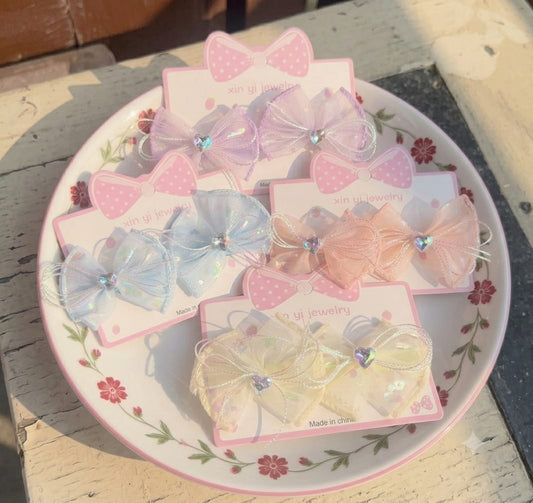 our pairs of pastel sheer mesh hair bow clips for kids with rhinestone heart centers on a decorative plate.