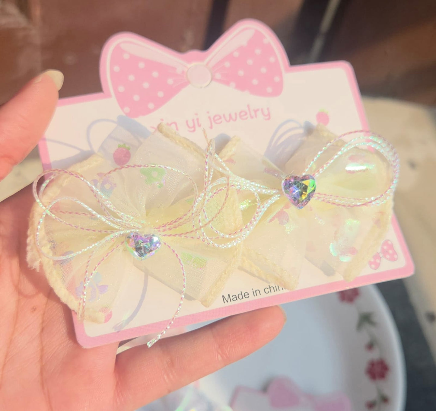 Pair of creamy yellow sheer mesh hair accessories for kids styled on a pink display card.