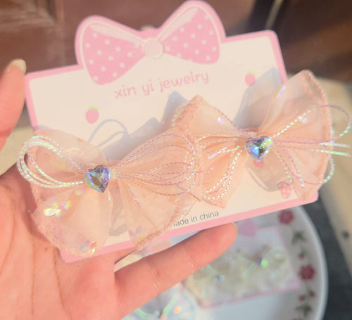 Pair of iridescent light orange organza mesh hair bow alligator clips for kids.
