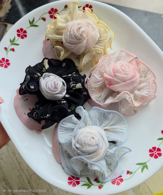 Set of four fabric floral rosette hair clips in pink, blue, yellow, and black on alligator clips.
