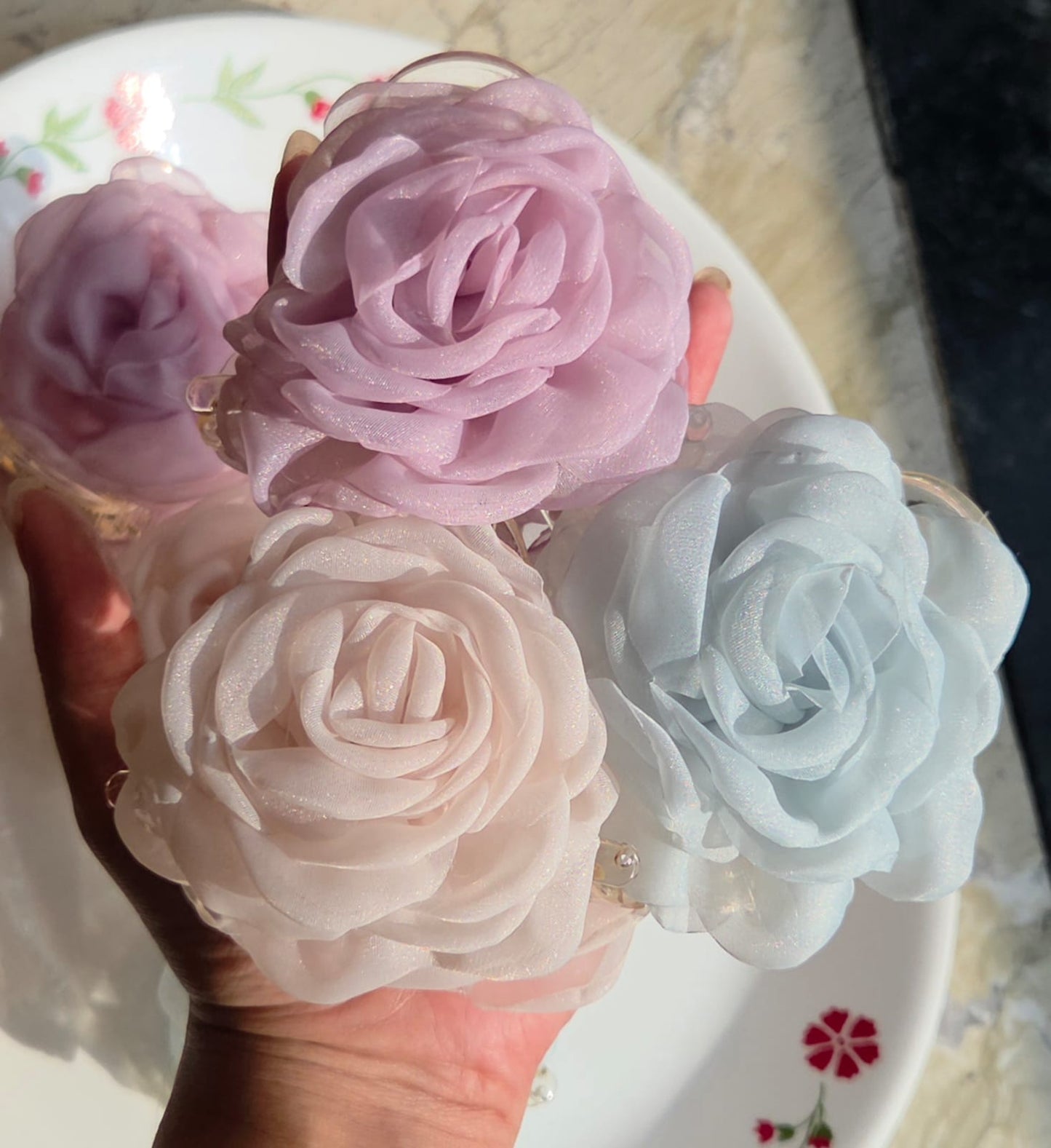    Three pastel organza rose flower hair claw clips in light blue, pink, and cream white held together.

