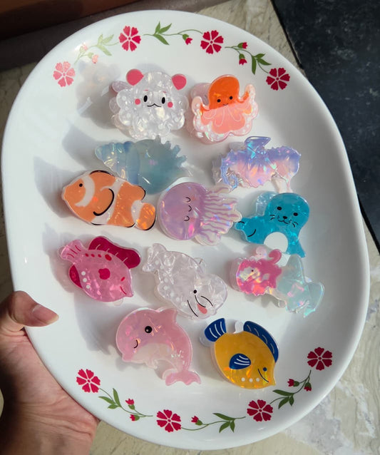    Collection of 12 cute iridescent ocean animal hair claw clips displayed on a dish
