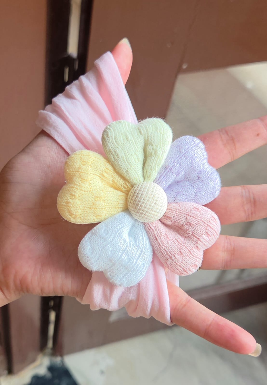   Soft pastel pink elastic hair band for baby girl featuring a comfortable plush flower
