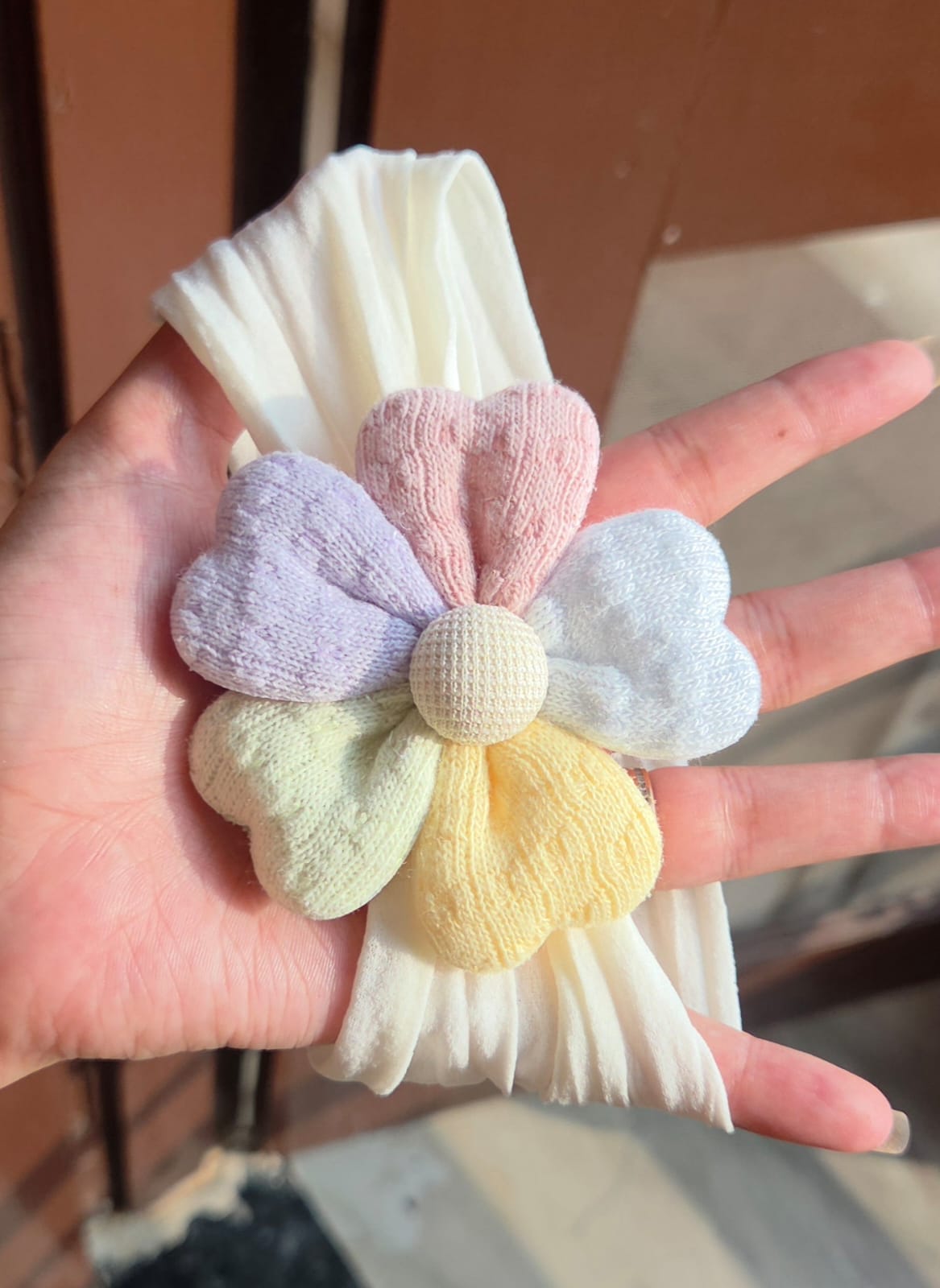    Soft off-white elastic baby headband with multi-colored pastel fabric flower embellishment
