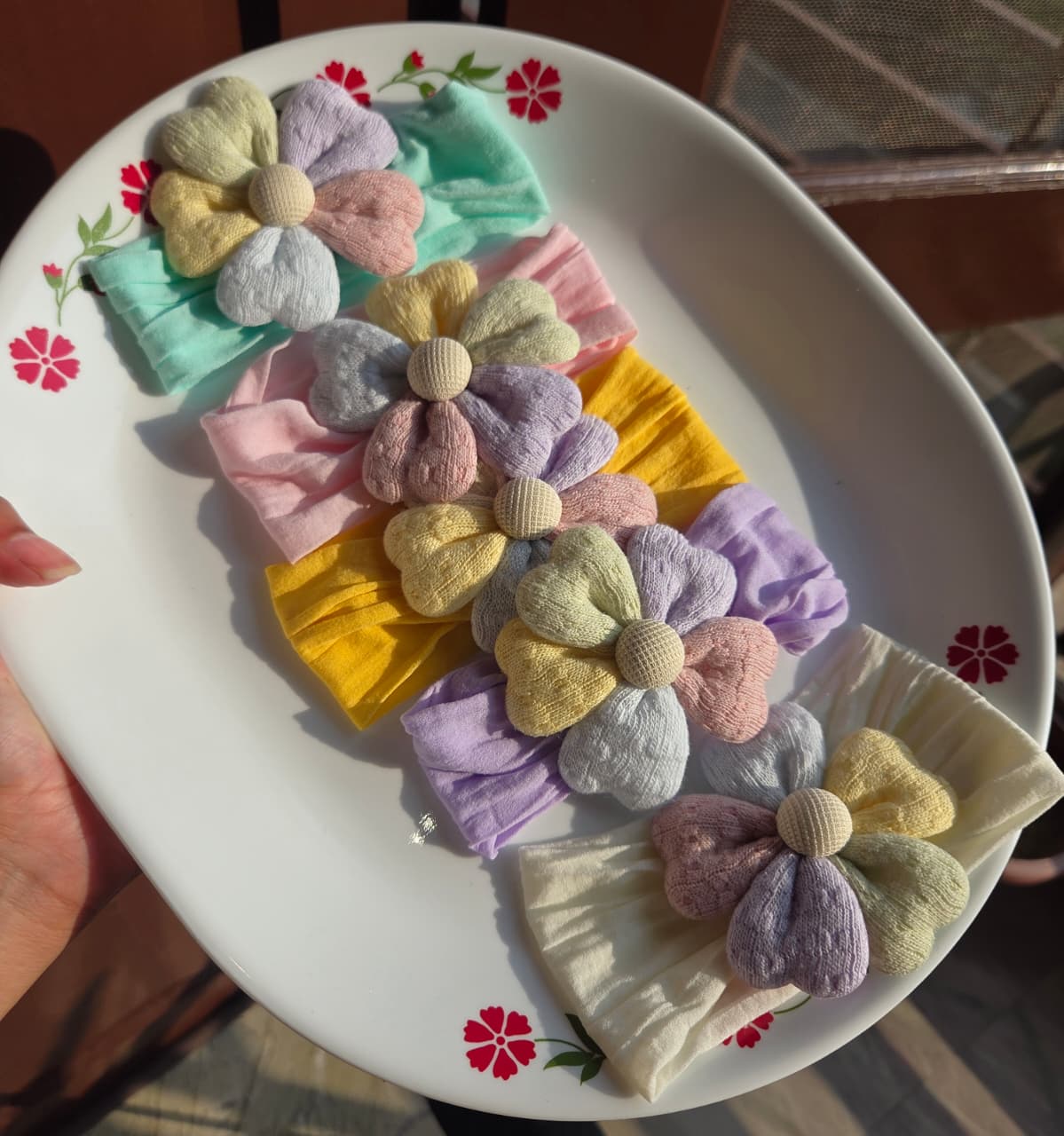    Collection of 6 soft fabric floral baby headbands in pastel yellow, pink, mint, purple, and coral on display
