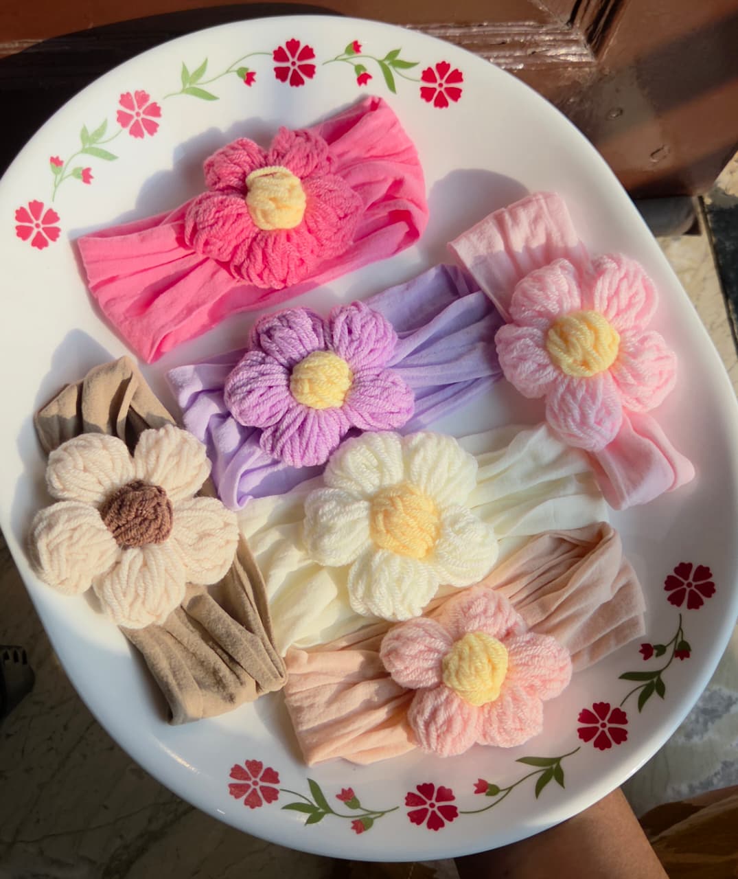 Soft stretchy baby nylon headbands with cozy yarn flower accents available in pink, purple, beige, peach, and cream color options.