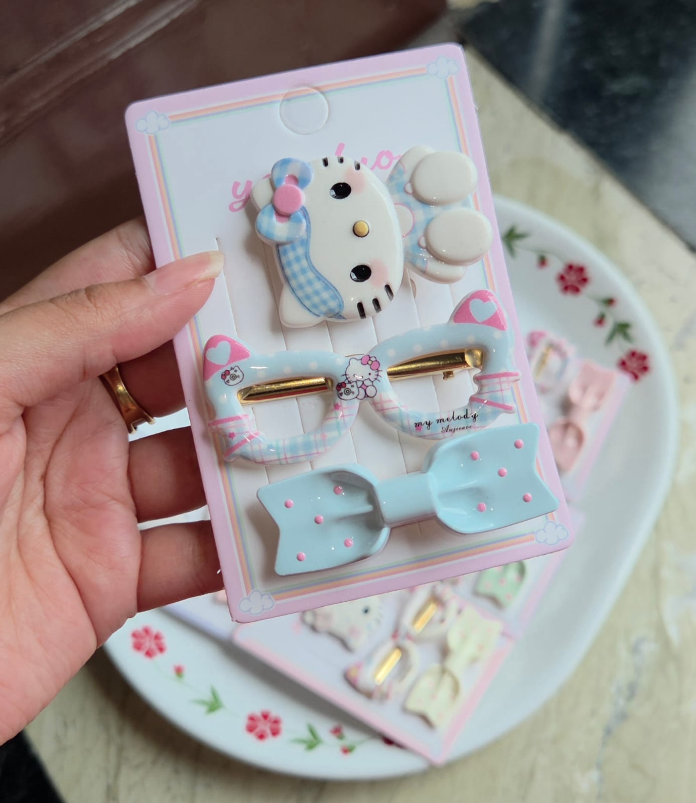    Light blue set of 3 hair clips with character face pin, printed oval clip, and polka dot bow clip.