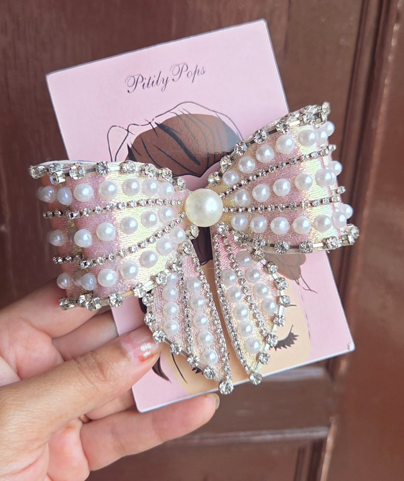 Large pearl and crystal rhinestone bow hair clip on pink Pitily Pops branded card held in hand