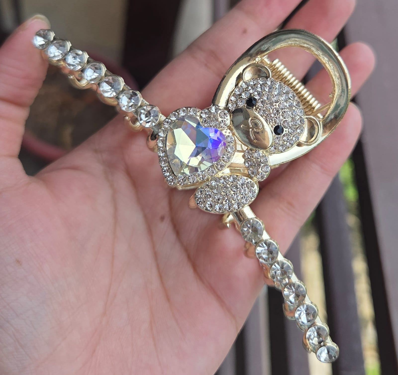 Close-up of a premium gold claw clip featuring a sparkling crystal-encrusted teddy bear holding a heart gem.