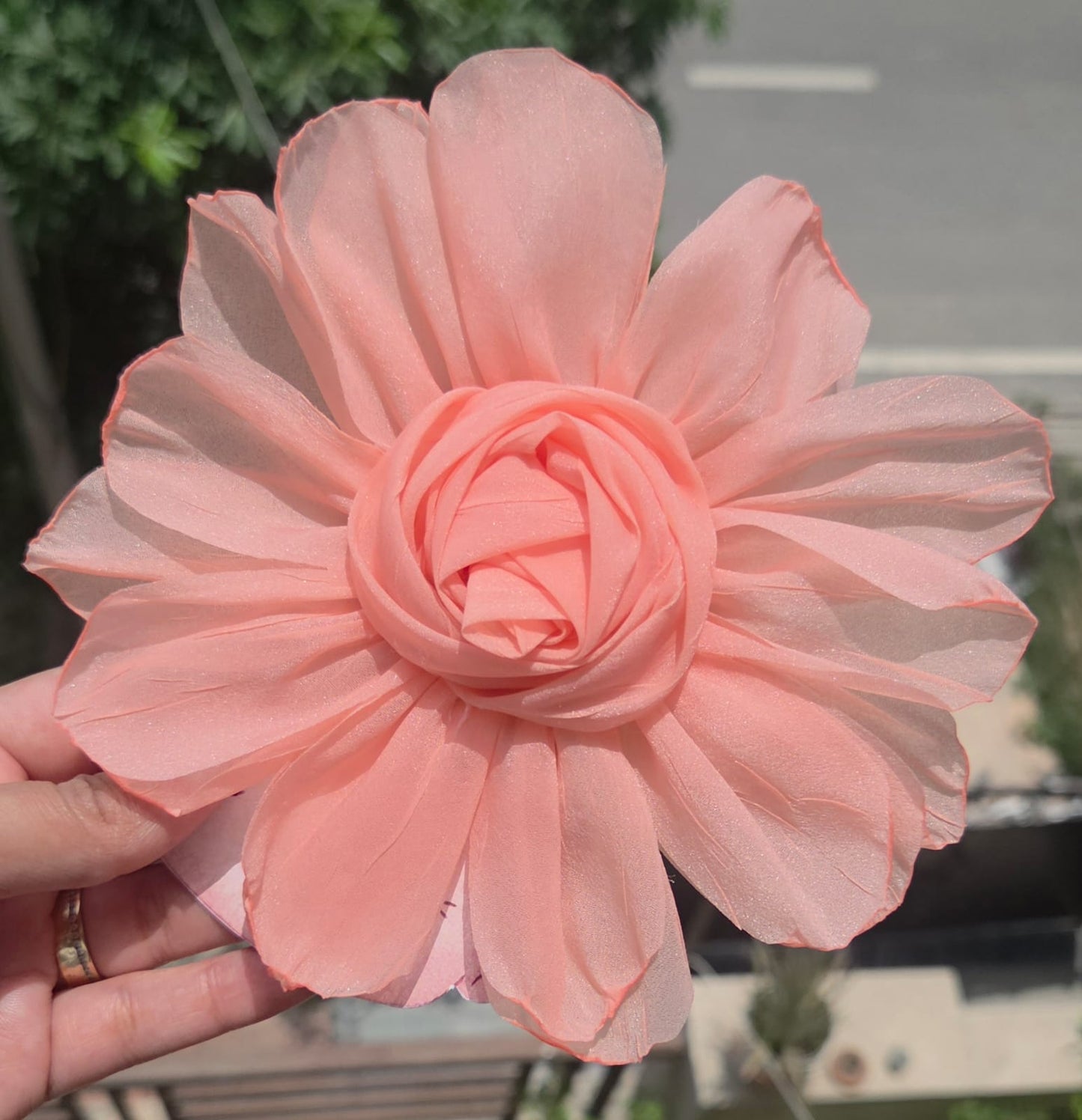    Soft peach orange floral hair accessory featuring a large fabric rosette with a secure metal alligator clip.
