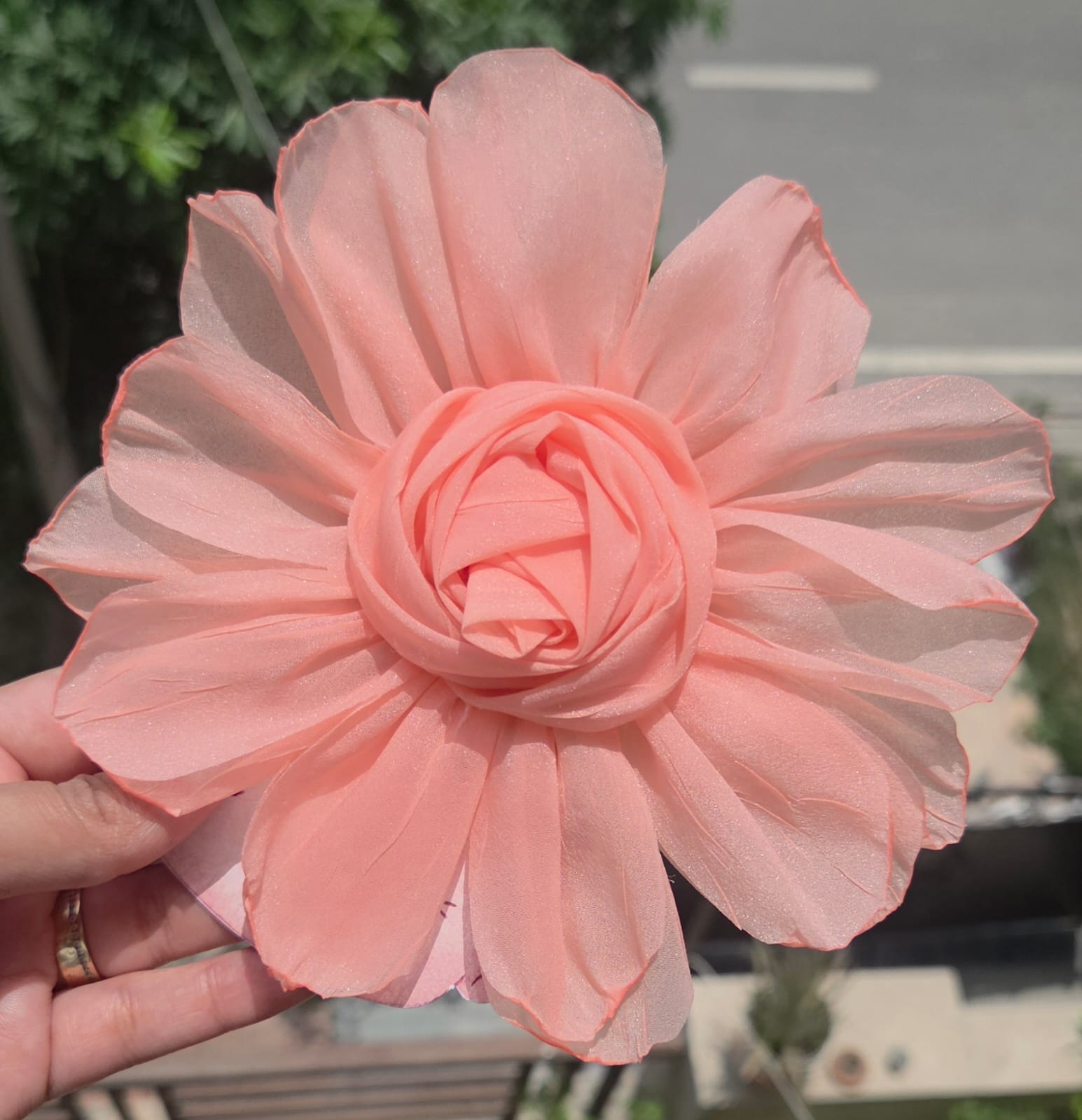    Soft peach orange floral hair accessory featuring a large fabric rosette with a secure metal alligator clip.
