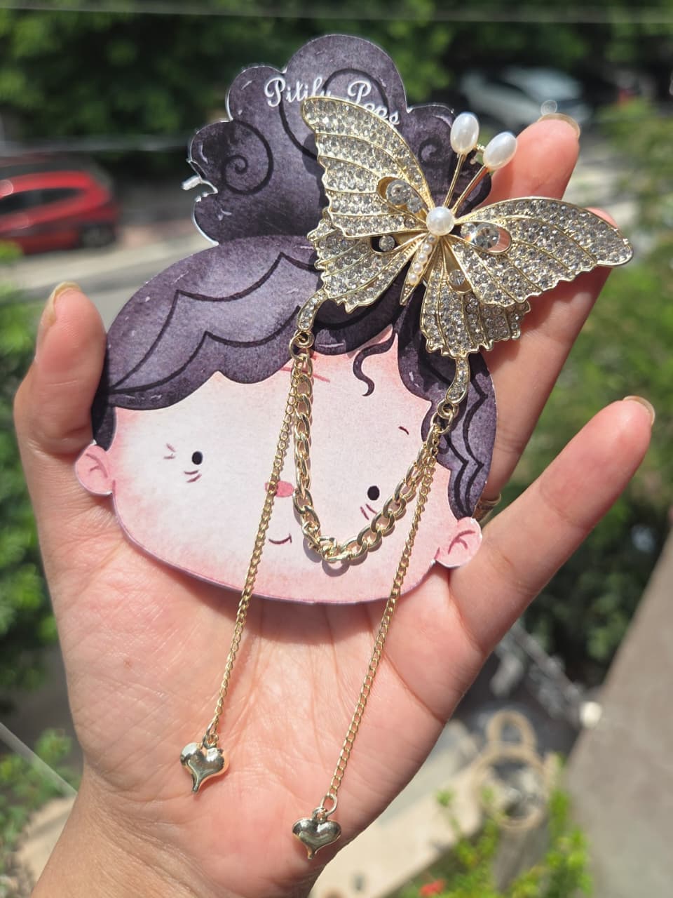 Close-up view of a premium rhinestone butterfly hair clip with gold dangling chains, showcasing the anti-tarnish metallic finish