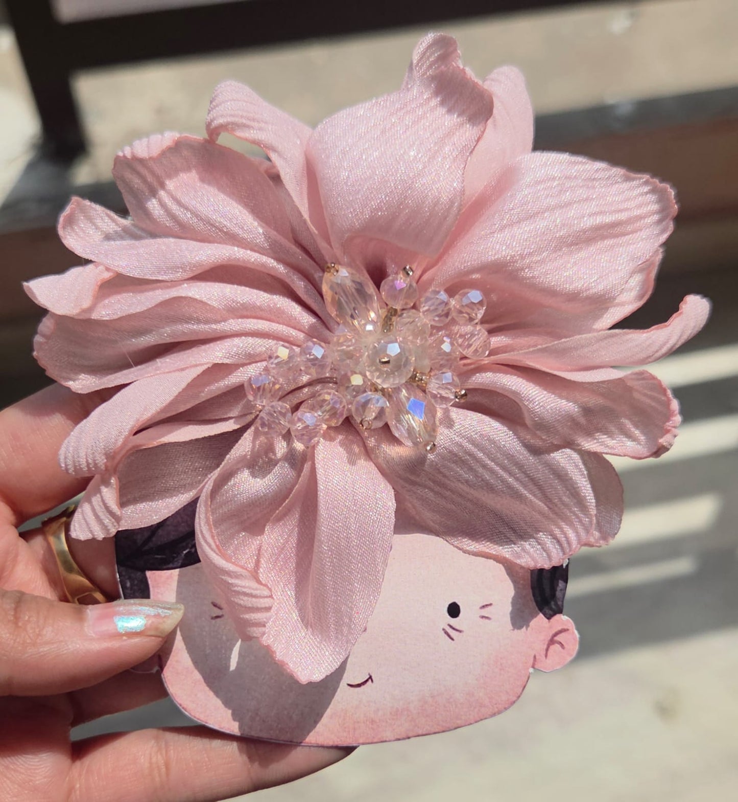 Soft blush pink fabric flower hair accessory with delicate shimmering pearl details at the center.