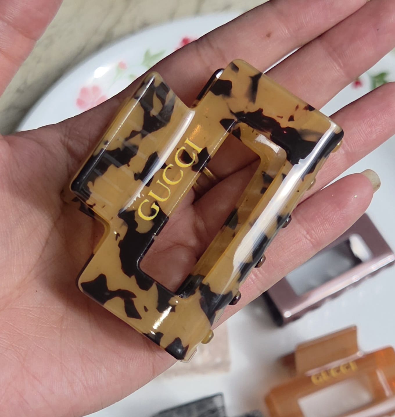   > "Yellow and black leopard tortoiseshell pattern rectangular hair claw clip on white surface."
