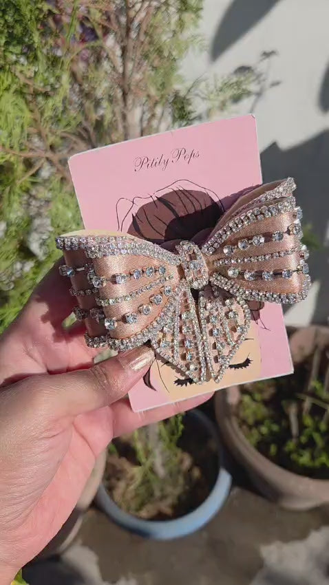 Premium luxury crystal statement hair bow with intricate rhinestone buckle detail in a champagne gold hue.