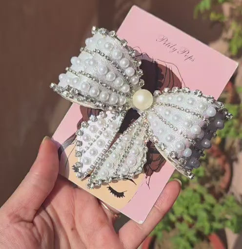Sky blue iridescent oversized hair bow clip with pearl rows and crystal rhinestone trim, displayed on a Pitily Pops branded card